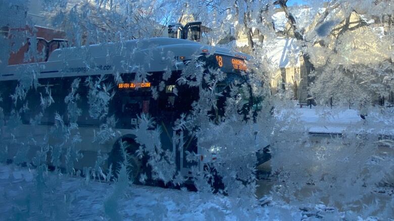 A bus can be seen through a pane of glass covered in ice.