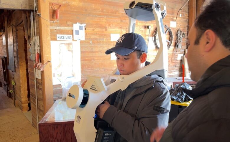 A student wears a large mobile mapping device, which sits on his shoulders, getting ready to try it for the first time. 