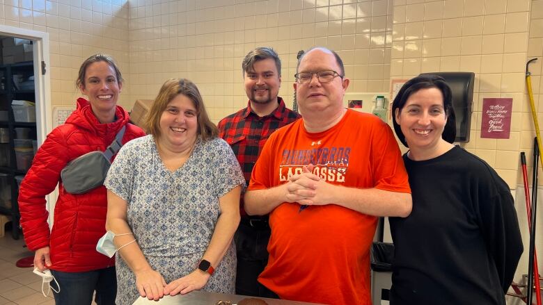 A group of five people smile for a photo.