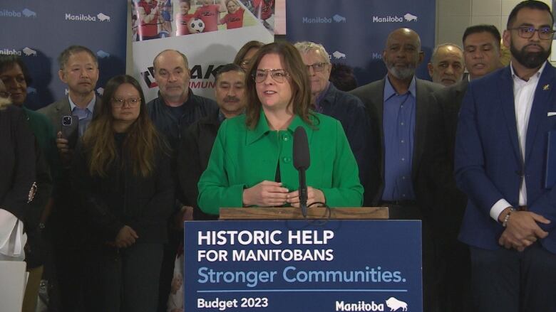 A women stands at a podium with people standing behind her.