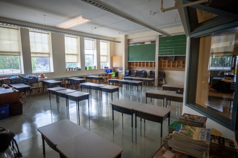 Empty desks are pictured in a classroom. 