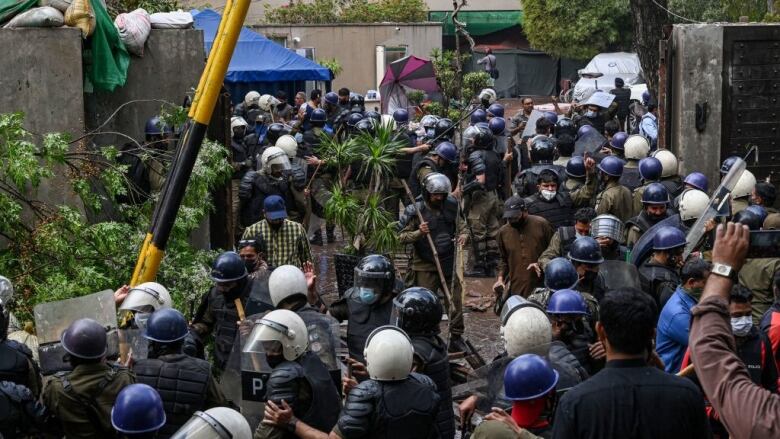 Riot police prepare to enter a home.