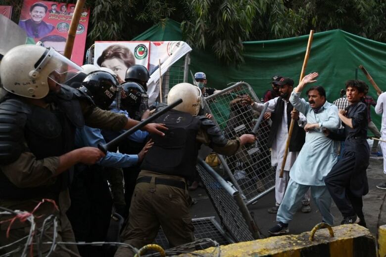 Riot police clash with a group of men.