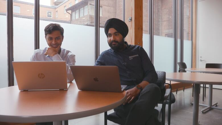 Two students look for sustainable investment opportunities on their laptops.