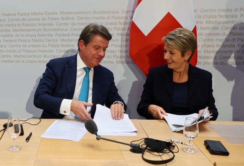 A man and a woman sit at a table for a press conference.