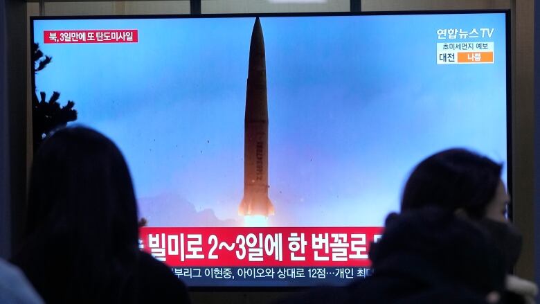 A TV screen shows a missile launch during a news program.