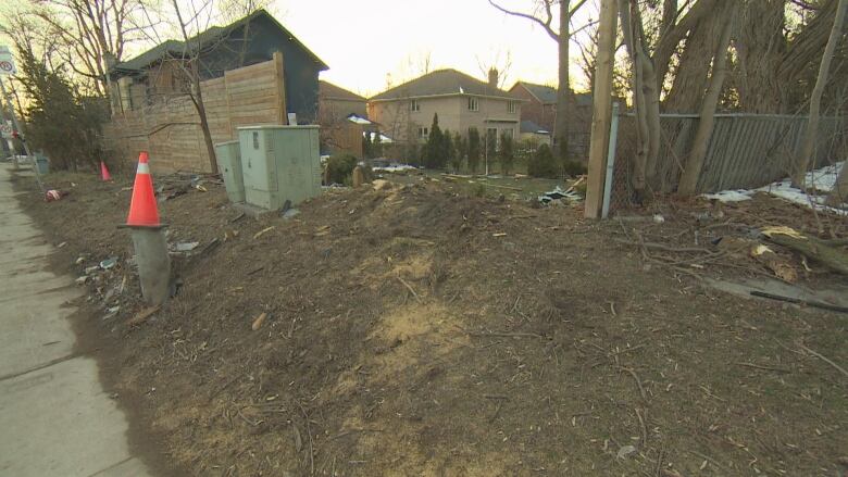 A fence enclosing a residential backyard is broken and pieces are scattered on the ground nearby.