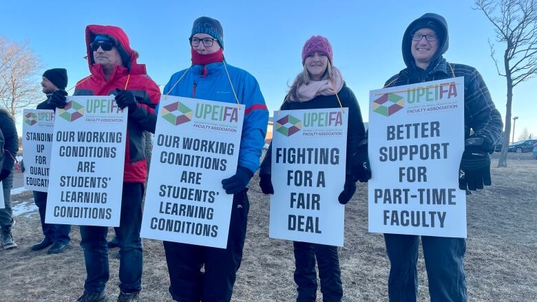 People standing outdoors, holding signs.