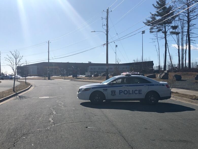 A police car is parked in front of a school. 