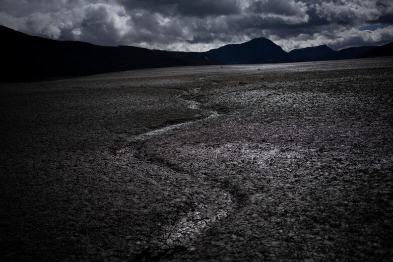 A dark, black and white image of a dry lakebed in France