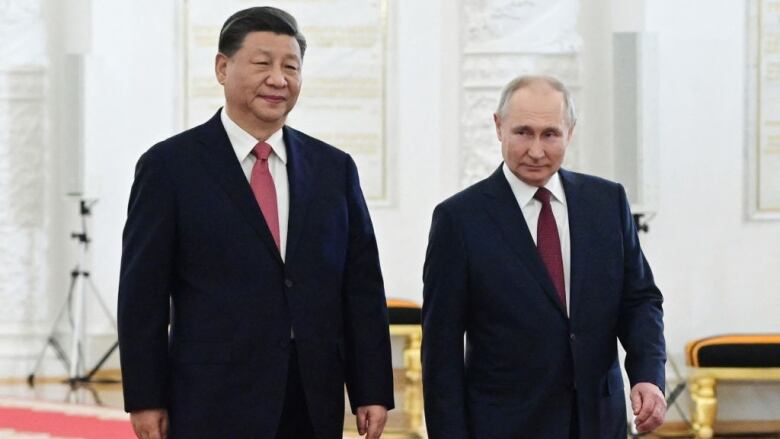 Chinese President Xi Jinping and Russian President Vladimir Putin walk together in the Kremlin in Moscow.