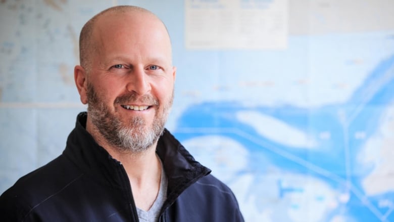 A man stands in front of a map of the Gulf of St. Lawrence