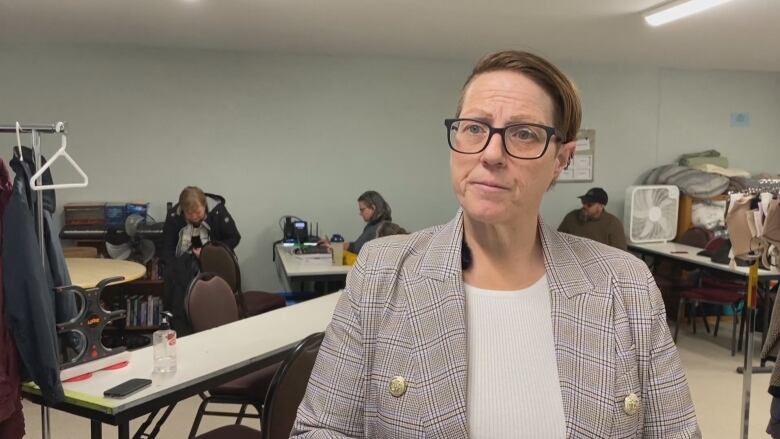 A woman wearing a plaid jacket talking to the camera. 