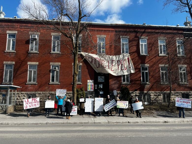 Brick building with people protesting out front