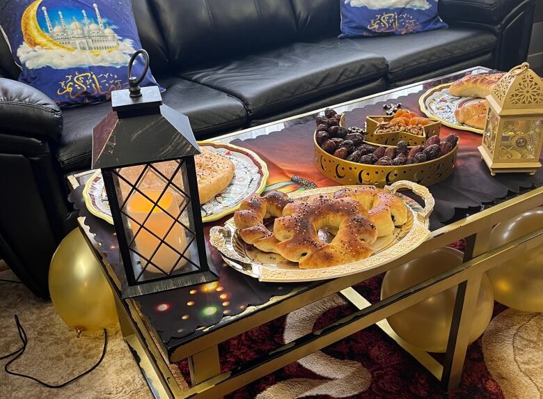 A spread of different Ramadan spreads and dates sit on a table nest to a lantern.