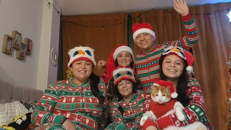 Family in matching Christmas pajamas on bed