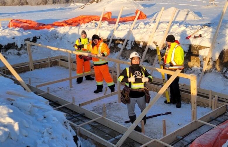 A group of women work outside doing construction in the winter. 