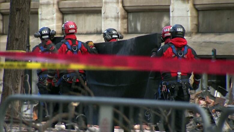 firefighters carrying black tarp