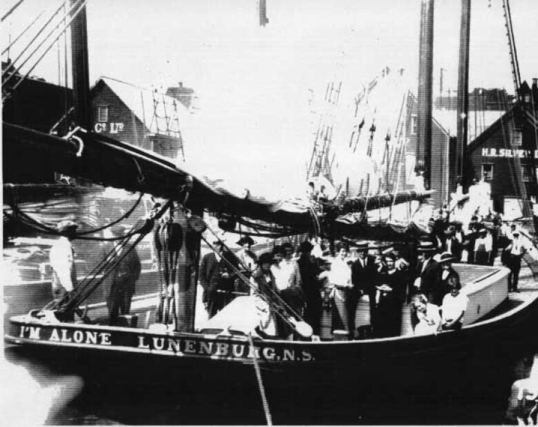 An old black-and-white photo of people on the I'm Alone ship with the sails down.