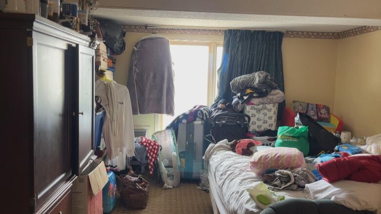 A motel room with lots of boxes and suitcases.