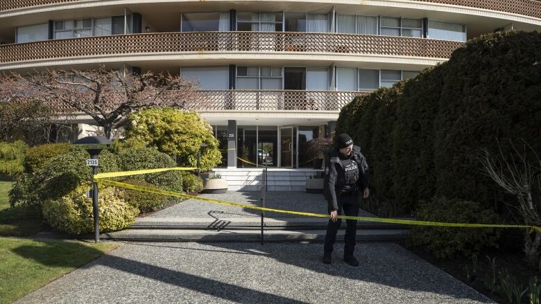 A West Vancouver police officer adjusts police tape in front of the scene of a homicide on Argyle Avenue. 