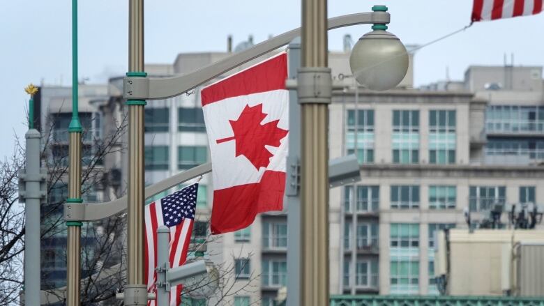 Several flags fly on flagpoles in front of a building.