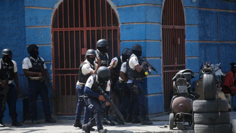 Police officers take cover during an anti-gang operation in the Lalue neighborhood of Port-au-Prince, Haiti, Friday, March 3, 2023.