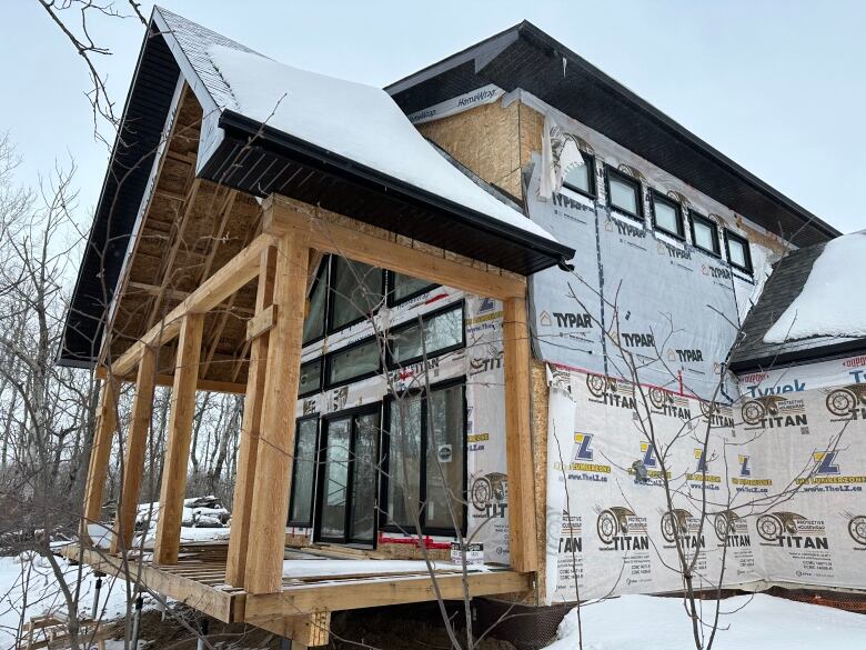 The exterior of an unfinished cabin, with bare beams and no siding, is shown.