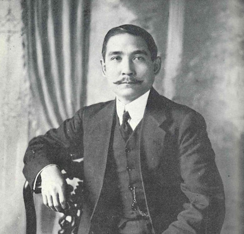 A man in suit sits on a chair.