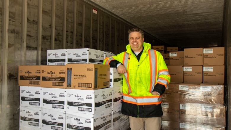 A man stands inside of a freight car filled with frozen potato products.