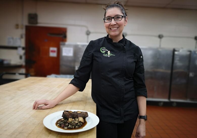 Chef Moser stands in the kitchen with a plate of freshly prepared game meat