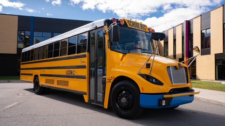 An electric school bus is parked outside a building.