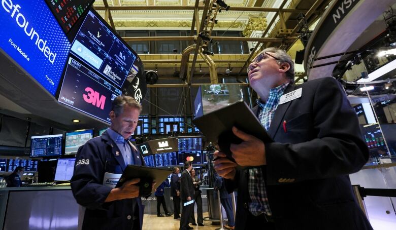 Men look at their computers surrounded by monitors at a stock exchange