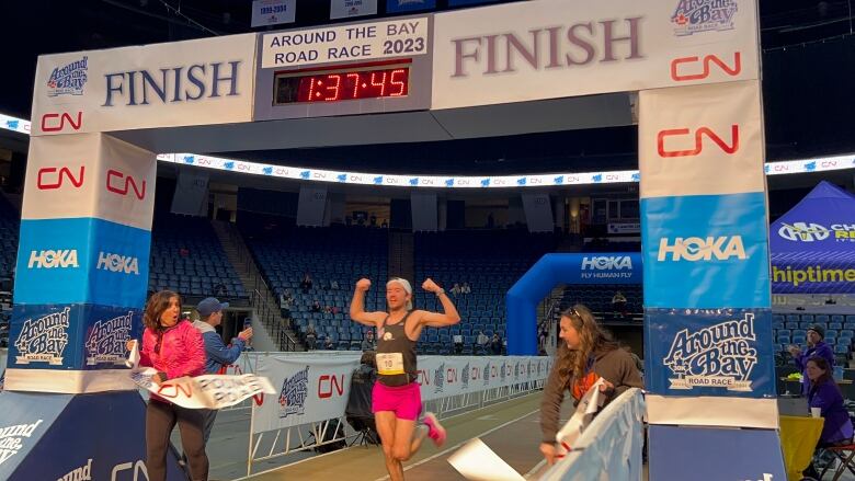 A man flexing his muscles as he arrives at the finish line.