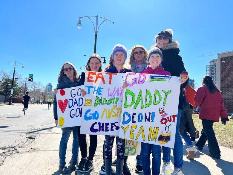 Three girls and three women holding signs in support of the kids' fathers.