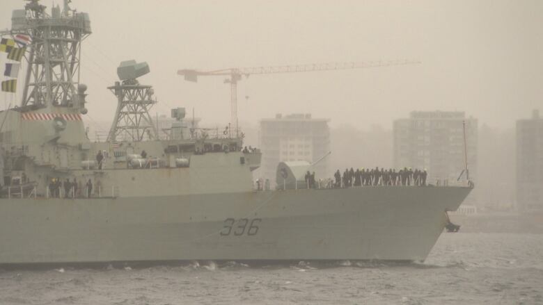 A hip with sailors on the deck sails in mist.