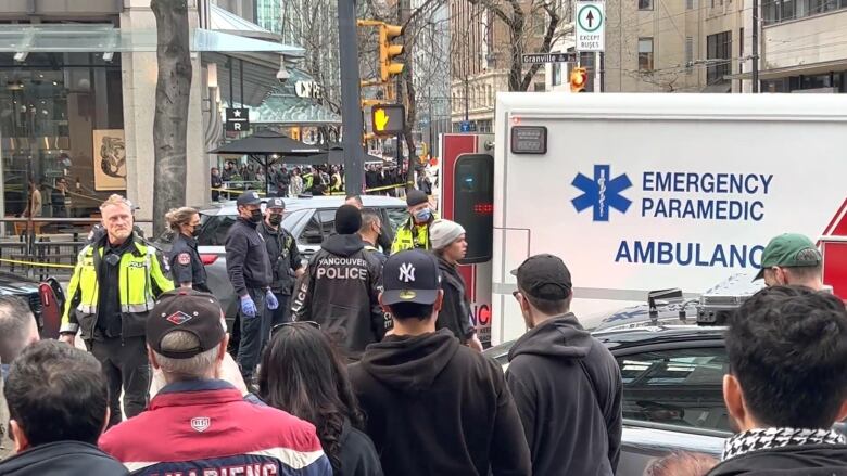 Emergency responders in uniform and an ambulance are pictured outside a Starbucks location at a busy street corner.