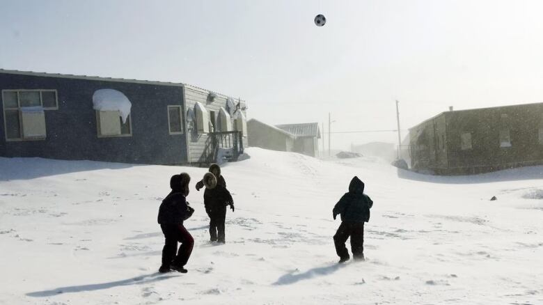 Three children playing soccer