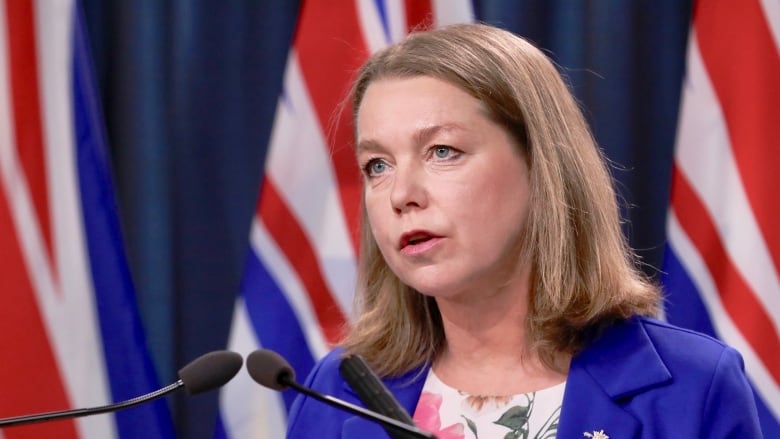 A woman in blue speaks in front of the microphone.