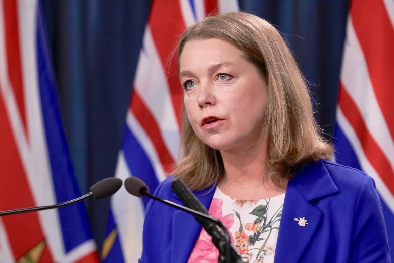 A woman in blue speaks in front of the microphone.