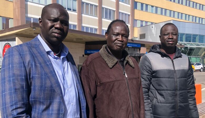 Three male members of Calgary's South Sudanese community stand outside the Calgary hospital. 