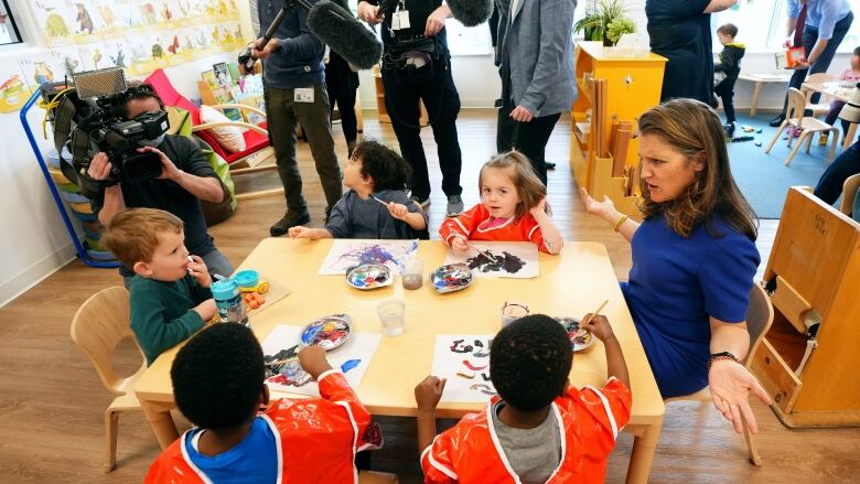 A politician at a table with kids during a photo op.