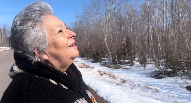 A woman stands outdoors looking at the camera