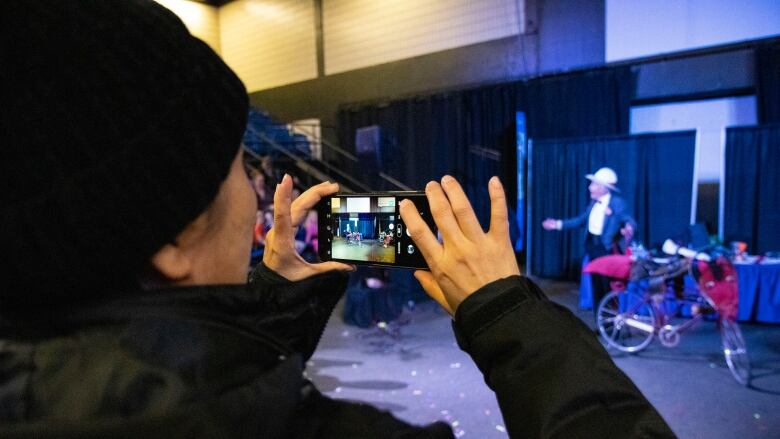 A person holds up a phone to record a man singing for a childrens show.