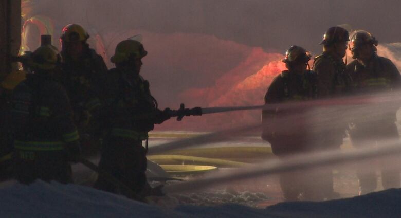 Firefighters are seen using water hoses to combat a fire.