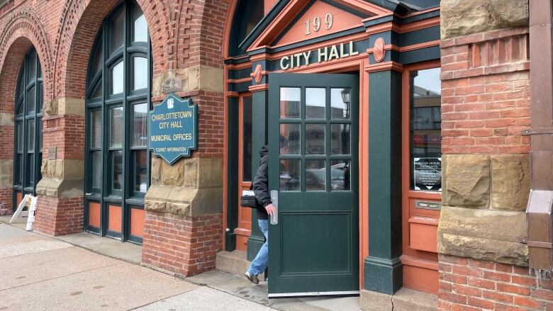 Someone walking in the main door of Charlottetown city hall.