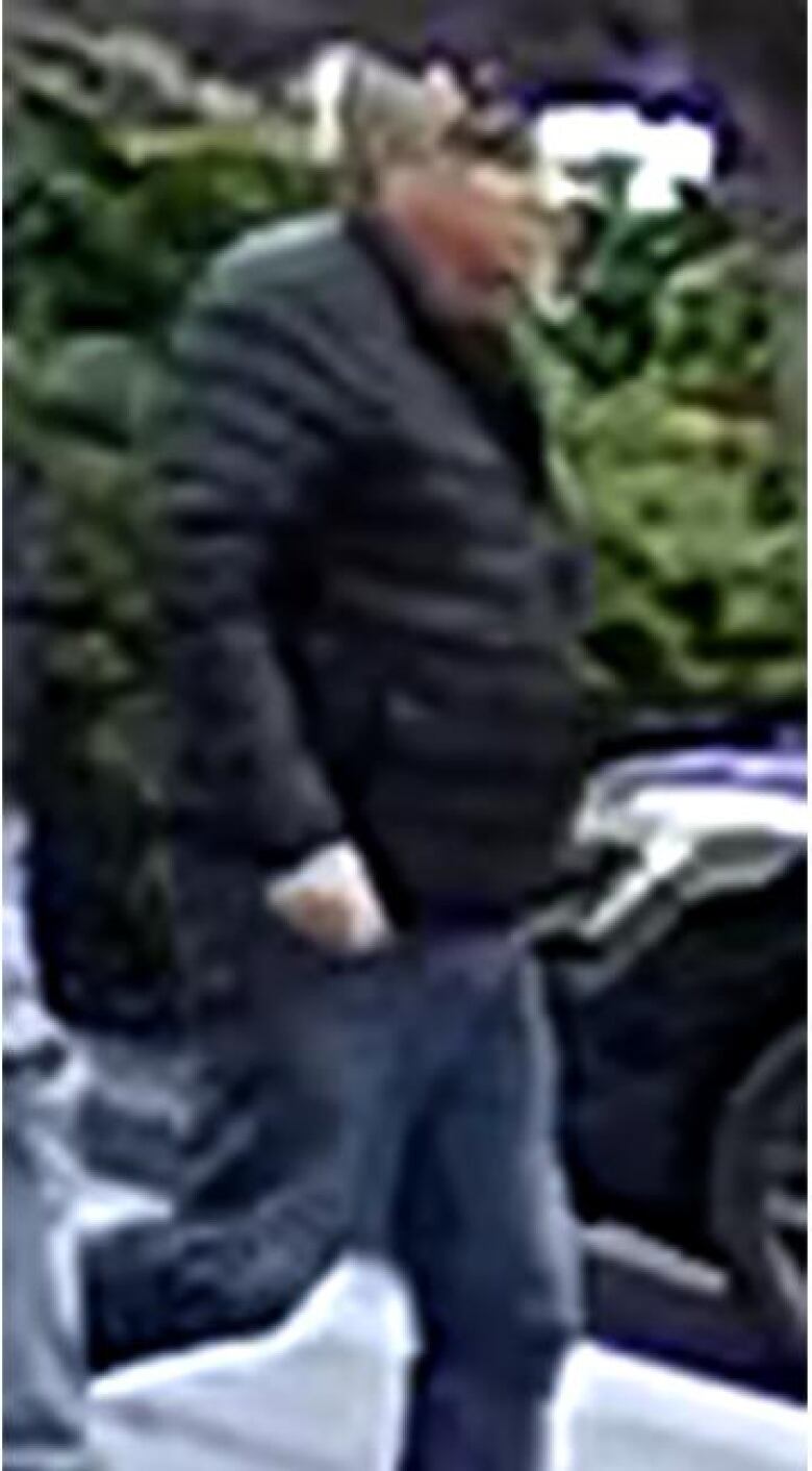 A grainy photograph of an older man in a black jacket and blue jeans.