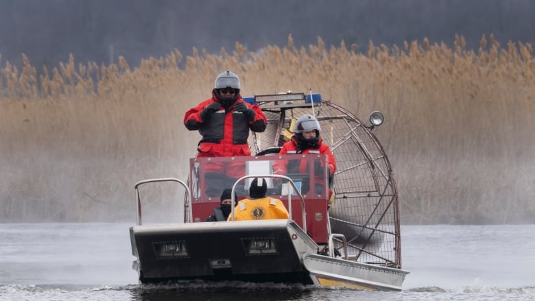 Search and rescue personnel ride a fan boat on a river. 