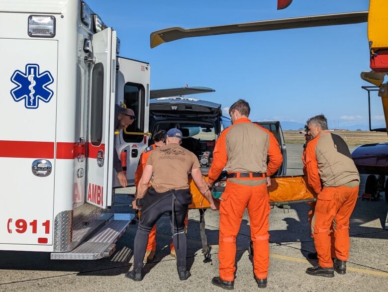 Someone is loaded into an ambulance by three men.