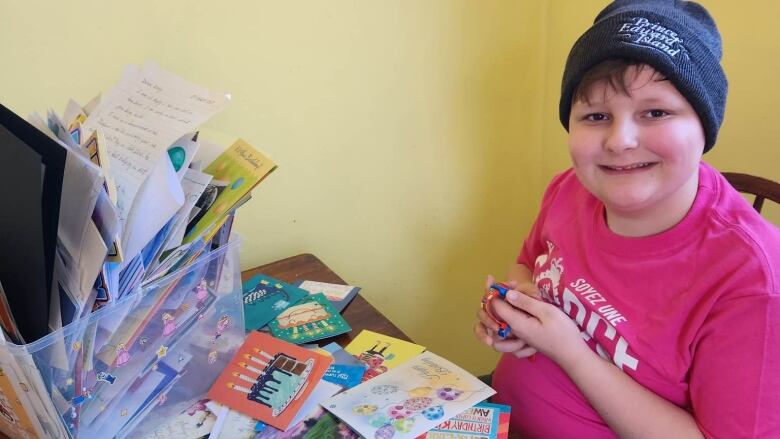 A child wearing a P.E.I. beanie and going through his birthday cards. 